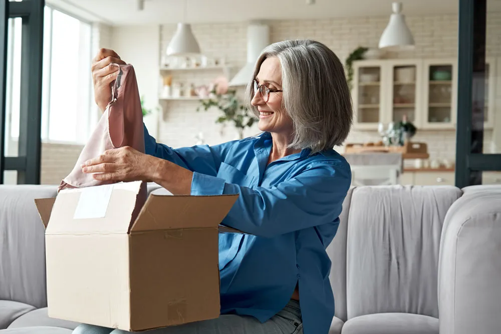 seorang wanita di rumah sedang membuka paketnya